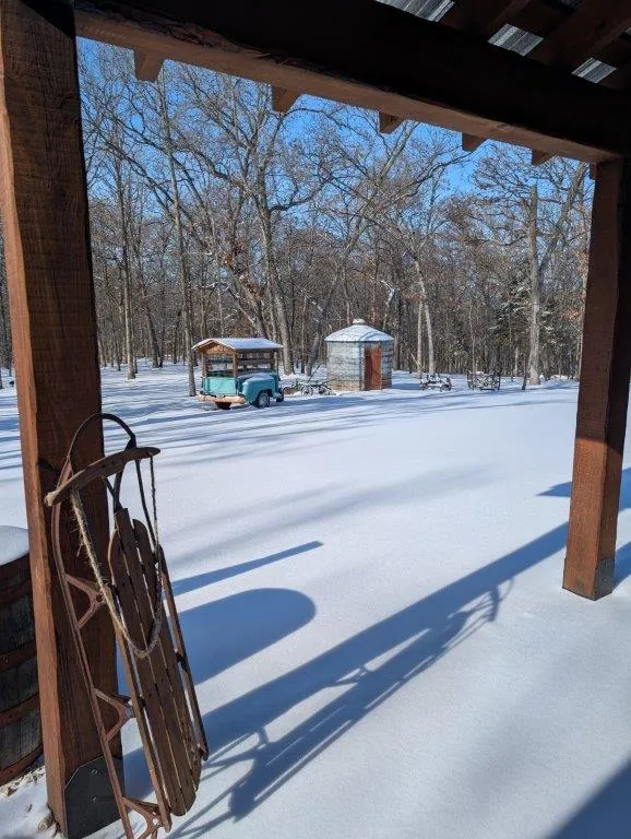 Porch view in winter with sled, teal truck, and outbuilding